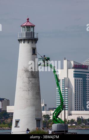Detroit, Michigan - Un travailleur sur un ascenseur peint le phare du parc d'État de Milliken. Le phare est situé sur la rivière Détroit, près du centre-ville de Détroit. Caesa Banque D'Images