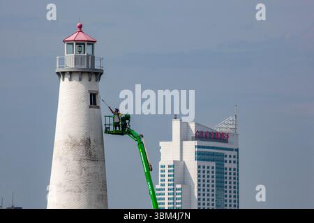 Detroit, Michigan - Un travailleur sur un ascenseur peint le phare du parc d'État de Milliken. Le phare est situé sur la rivière Détroit, près du centre-ville de Détroit. Le C Banque D'Images