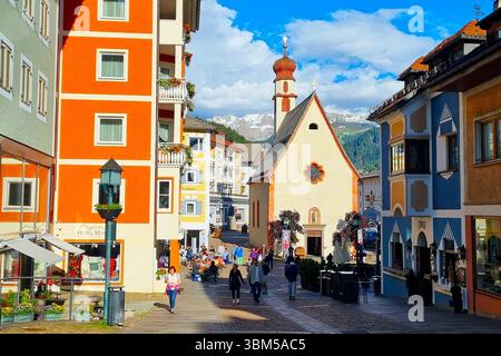 Une zone piétonne animée avec des touristes inconnus se promenant dans la station balnéaire d'Ortisei dans le centre de la pittoresque vallée de Val-Gardena dans les Dolomites Banque D'Images