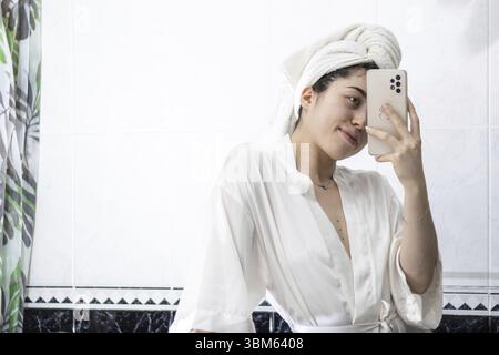 Photo d'une femme prenant un selfie alors qu'elle portait une serviette sur la tête Banque D'Images