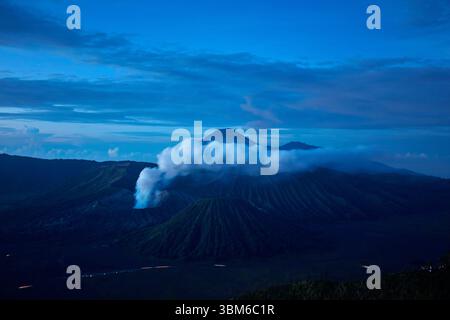 Fumée et vapeur venant du Mont bromo (Gunung bromo) à l'aube, avec le Mont Semeru fumant au loin, Java oriental, Indonésie Banque D'Images