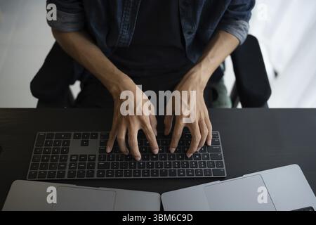 Homme asiatique ingénieur logiciel travaillant sur l'ordinateur au bureau pour écrire le code de programme IT ingénieur logiciel trouver des erreurs tech support devops creati Banque D'Images