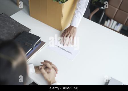 Homme d'affaires envoyant une lettre de démission au patron et tenant des choses démissionnent déprimer ou portant boîte en carton par bureau dans le bureau Banque D'Images