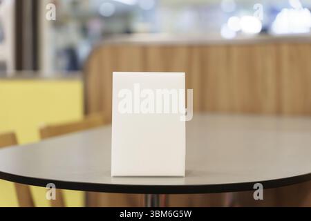 Maquette de menu vierge pour la promotion marketing textuelle. Maquette cadre de menu debout sur une table en bois dans l'espace du restaurant pour le texte Banque D'Images