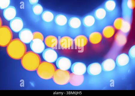 Guirlandes néon rouge bleu jaune de lumières bokeh. Fond festif de couleurs rétro Banque D'Images