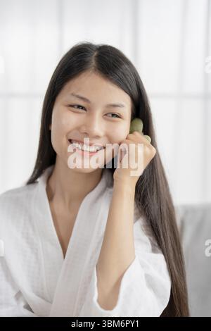 Routine de beauté quotidienne femme asiatique se soin de soi faire un massage facial gua Sha médecine traditionnelle Gua Sha pierre de quartz cosmétique tendance naturelle Banque D'Images