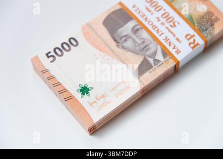 Pekanbaru, Indonésie - 21 mars 2025 : une pile de billets de banque rupiah indonésiens RP 5,000 isolés sur fond blanc pour THR sur Eid al-Fitr ou Lebaran Banque D'Images