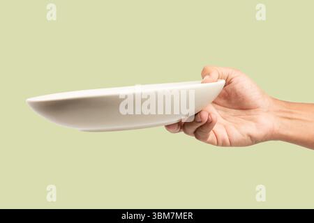 Main masculine tenant un plat de soupe beige isolé sur fond vert Banque D'Images