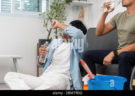 Relaxation et hydratation. Jeune homme essuyant les larmes tout en tenant une bouteille d'eau. Banque D'Images