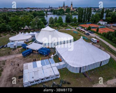 Schwerin, Allemagne. 24 juin 2025. Les acteurs, musiciens et techniciens du Théâtre d'État de Mecklembourg travaillent dans trois tentes et conteneurs spéciaux et répètent pour l'opérette 'la veuve joyeuse'. (Vue aérienne avec un drone). En raison de travaux de construction importants dans le bâtiment historique de la scène, six productions sont prévues pour la saison 2025/2026 dans la tente de théâtre sur le lac Schwerin. En plus des pièces de théâtre, ballets, opéras et opérettes, l'Orchestre d'État de Mecklembourg jouera également ses concerts dans la tente. Crédit : Jens Büttner/dpa/Alamy Live News Banque D'Images