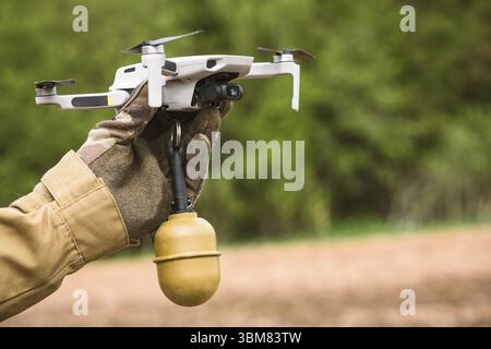 Opérateur dans des vêtements de couleur militaire tient dans la main préparant un drone pour le vol attaché grenade en plein air Banque D'Images