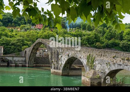 Vieux pont du Diable en pierre traversant la rivière verte avec des arbres et des collines en Toscane, Italie. Photo de haute qualité Banque D'Images