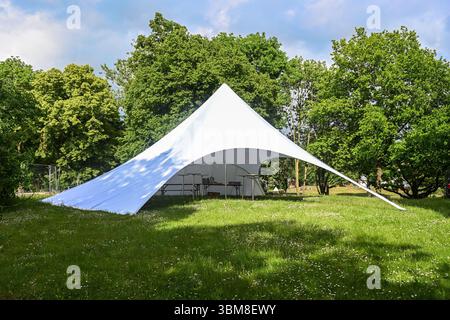 Grande tente de fête en toile blanche avec ouvertures variables sur une prairie dans le parc pour un festival d'été, espace copie, focus sélectionné Banque D'Images