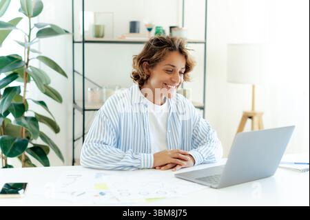 Heureuse femme brésilienne confiante souriante et écoutant ses collègues lors d'une réunion virtuelle. Femme d'affaires engagée dans la conversation en ligne, parler avec les clients avec intérêt et positivité Banque D'Images