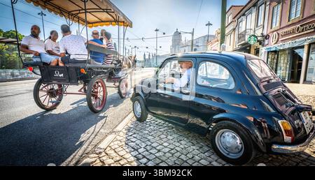 Fiat 500 vintage et calèche touristique tirée par des chevaux dans les rues pavées du quartier historique de Belém, Lisbonne, mettant en valeur les transports traditionnels Banque D'Images