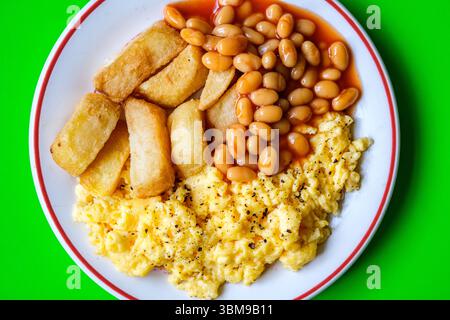Londres Royaume-Uni juin 25 2025, brouille les œufs avec les haricots cuits dans la sauce tomate et les chips frites épaisses Banque D'Images