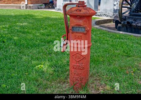 Toujours en service une vieille bouche d'incendie municipale peinte en rouge vif avec une serrure sur le côté vue rapprochée à l'extérieur Banque D'Images