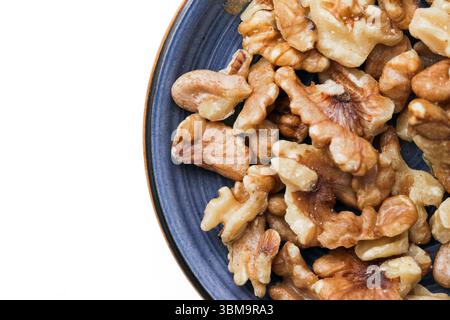 Noix dans un bol en céramique. Brunir les cerneaux de noix sur une plaque bleue. En-cas sains et aliments riches en protéines. Fond naturel de superaliment. Noix biologiques pour l'alimentation. Banque D'Images