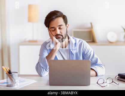 Entrepreneur arabe trop travaillé assis à la table dans le bureau et en veille Banque D'Images