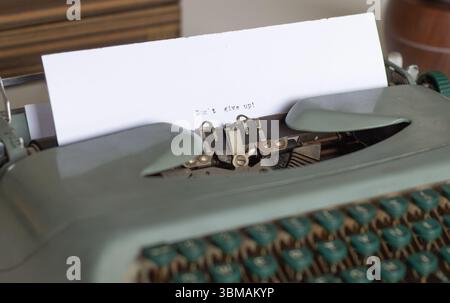 Gros plan d'une machine à écrire vintage affichant le message encourageant n'abandonnez pas, inspirant persévérance et détermination face aux défis Banque D'Images