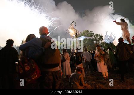 Londres, Royaume-Uni. 25 juin 2025. La zone Green Fields du Festival de Glastonbury s'ouvre ce soir avec une cérémonie dirigée par la « flamme de l'espoir » partagée, réunissant 15 flammes sacrées du monde entier. Un refrain de plus de mille voix chante un mantra de paix dans King's Meadow suivi d'un spectaculaire feu d'artifice. L’événement crée un puissant sentiment d’unité et de but, marquant le début officiel du festival dans ce calme et spirituel cœur du site crédit : Joao Daniel Pereira/Alamy Live News Banque D'Images