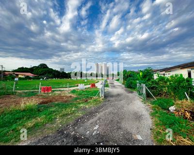 Vue grand angle d'un champ d'équitation vide capturé depuis la clôture avant, avec un ciel dégagé et un bâtiment visible en arrière-plan. Banque D'Images
