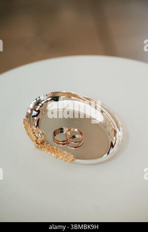 Paire de bandes de mariage en or jaune classique reposant sur un plateau en argent orné Banque D'Images