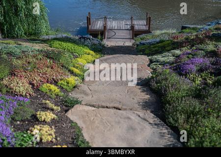 Une vue sereine sur le lac accompagnée d'un chemin de jardin dynamique et accueillant menant à travers la nature Banque D'Images