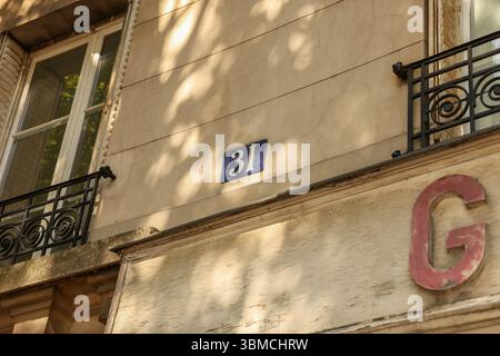 Gros plan de la façade d'un bâtiment parisien, présentant des détails architecturaux tels que le numéro 31 sur une plaque bleue Banque D'Images