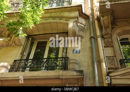 Gros plan détaillé d'un élégant balcon parisien, présentant des ferronneries complexes et des détails architecturaux. Banque D'Images