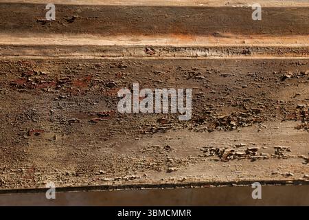 Un gros plan détaillé révèle une surface texturée de bois brun vieilli avec un décollement important de la peinture, exposant des nuances rougeâtres. La vitrine des images Banque D'Images