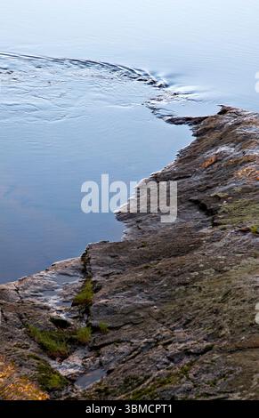 Eau ondulant de l'extrémité d'un rocher au bord de l'eau. Llyn Padarn Snowdonia, Gwynedd, pays de Galles, Royaume-Uni Banque D'Images