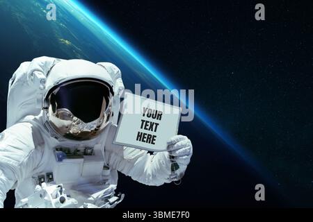 Spaceman in Open Space montre Une carte avec votre texte ici sur le fond de la planète Terre. Astronaute avec message publicitaire Banque D'Images