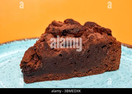 Une seule tranche d'un gâteau au chocolat au caramel servi sur une assiette sur un fond Uni Banque D'Images