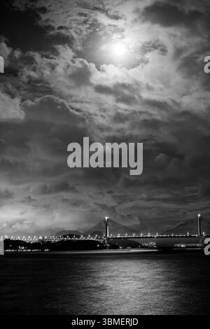 Image en noir et blanc du pont de Tsing ma à Hong Kong, illuminé par le clair de lune, avec un ciel spectaculaire rempli de nuages Banque D'Images