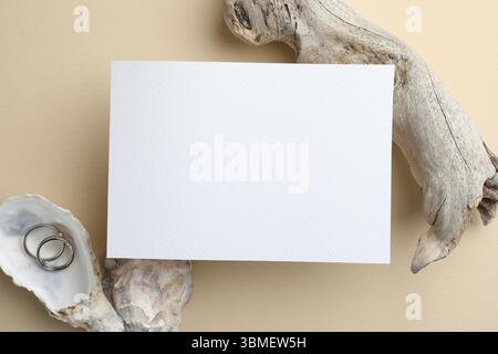 Carte d'invitation de mariage, bagues en argent et décor sur fond beige, plat Banque D'Images