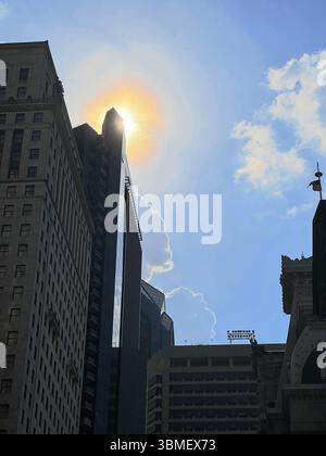 Soleil derrière Une tour de gratte-ciel Banque D'Images