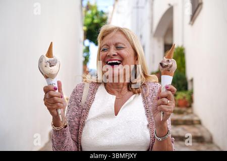 Femme âgée heureuse appréciant deux glaces en été. Banque D'Images