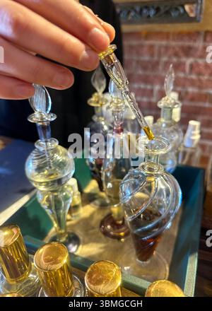 Gros plan de petites bouteilles de parfum artisanal et d'huile essentielle, avec la main d'une femme à l'aide d'une pipette. Banque D'Images