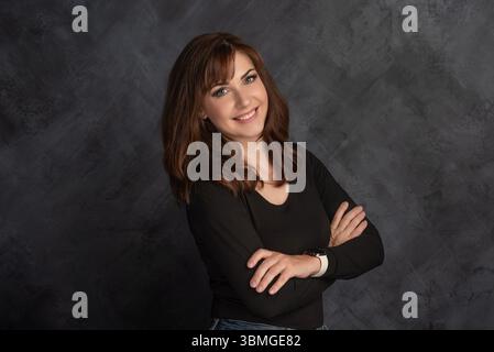 Femme souriante confiante avec les bras croisés en top noir Banque D'Images