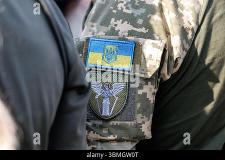 16 juin 2025, Ukraine, Butscha : le drapeau ukrainien avec le trident, connu sous le nom de Trysub (emblème national de l'Ukraine et symbole national important), et un patch avec l'image d'une femme armée avec des ailes d'ange peuvent être vus sur l'uniforme militaire d'une femme soldat de l'unité mobile de défense aérienne volontaire 'sorcières de Bouksha' à Bouksha près de Kiev, la capitale de l'Ukraine, le 16 juin 2025. Les « sorcières de Butsha » ne font pas partie de l'armée, mais une unité de volontaires subordonnée au gouvernement régional qui surveille le ciel au-dessus de Butsha contre les attaques de drones russes. Photo : Matthias Balk/dpa Banque D'Images