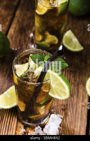 Cuba Libre fait maison avec de la chaux, de rhum brun et de la glace concassée sur une vieille table en bois Banque D'Images