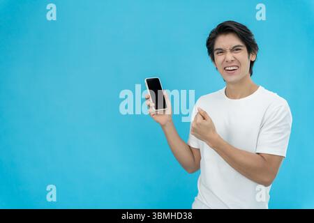 L'homme beau asiatique est sorti de l'expression de visage surprise. Masculin se sent choqué avec le téléphone. sourire passionnant et joyeuses réjouissances adorables. Très agréable et amusant Banque D'Images