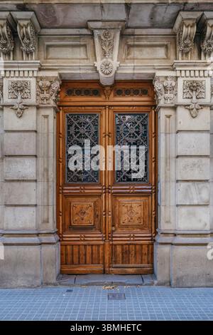 Porte d'entrée en bois d'Un bâtiment classique de Barcelone, ornée de sculptures en pierre. Architecture espagnole historique, façade urbaine, éléments décoratifs, C Banque D'Images
