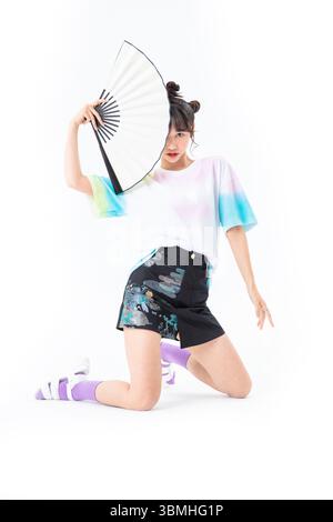 Une belle jeune étudiante dans une jupe courte de style chinois tient un papier traditionnel chinois fan​ Banque D'Images