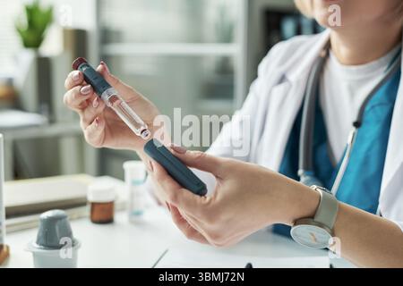 Caucasien femme d'âge moyen préparant l'injection d'insuline pour le traitement du diabète dans le cabinet médical, tenant le stylo d'insuline et le flacon tandis que l'explainin Banque D'Images