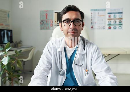 Portrait d'un médecin caucasien d'âge moyen portant des lunettes assis dans le cabinet médical regardant la caméra avec stéthoscope autour du cou, conscient du diabète Banque D'Images
