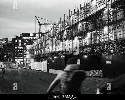 Royaume-Uni, Londres, 30 juin 2025. Vue en soirée de l'échafaudage du chantier de construction illuminé par les cyclistes qui passent dans un réaménagement du centre de Londres Banque D'Images