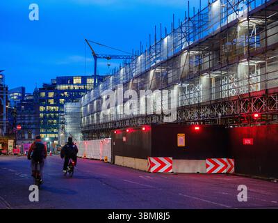 Royaume-Uni, Londres, 30 juin 2025. Vue en soirée de l'échafaudage du chantier de construction illuminé par les cyclistes qui passent dans un réaménagement du centre de Londres Banque D'Images