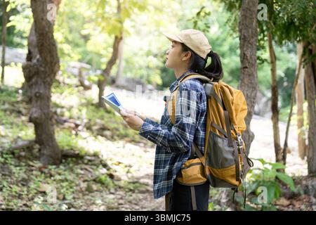 Navigation en plein air. Jeune femme utilisant la carte tout en faisant de la randonnée dans une forêt. Banque D'Images
